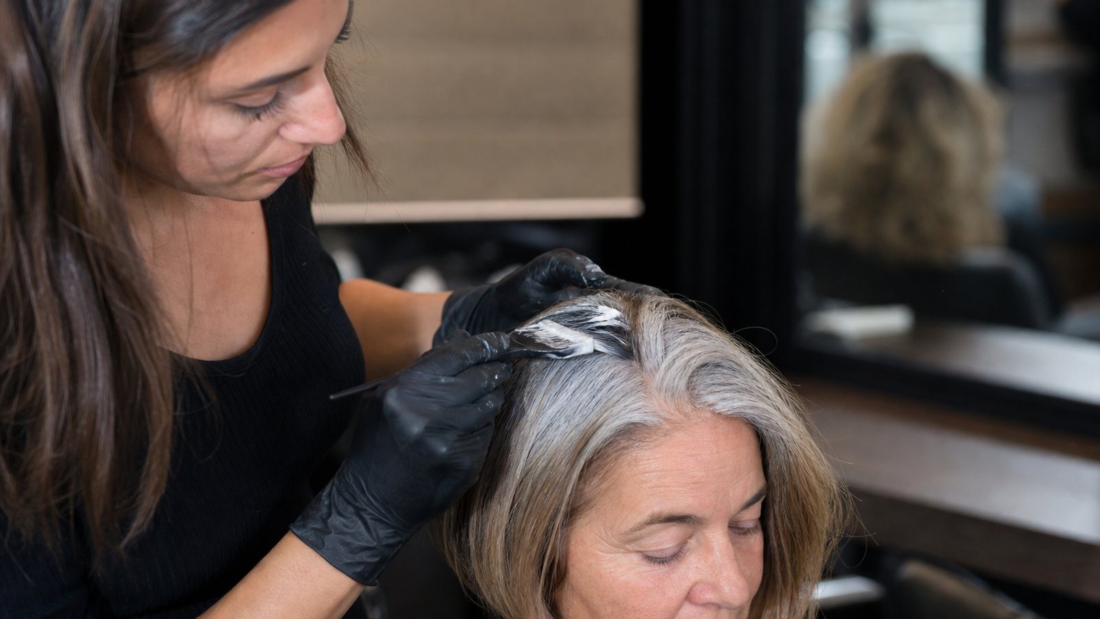Coloriste écartant une mèche pour estimer la proportion de cheveux blancs aux tempes