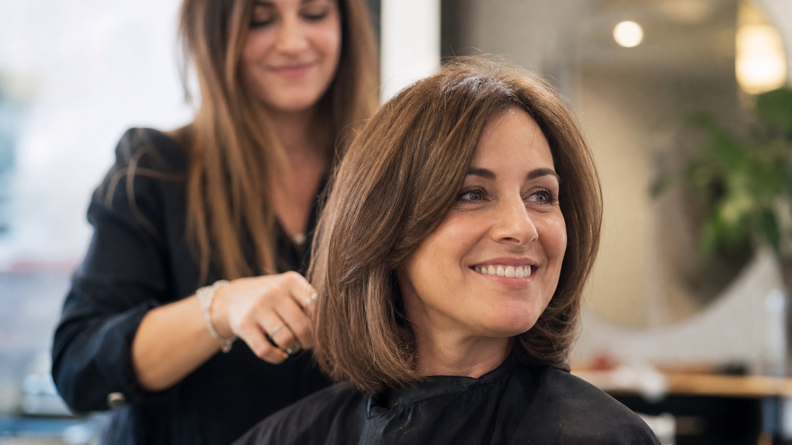 Cliente fidèle souriant devant le miroir, satisfaite de sa couleur constante